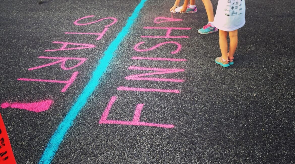 girl writing on the ground using a spray an