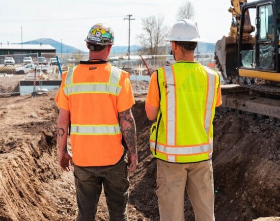 men in safety vests standing in front of a construction vehicle