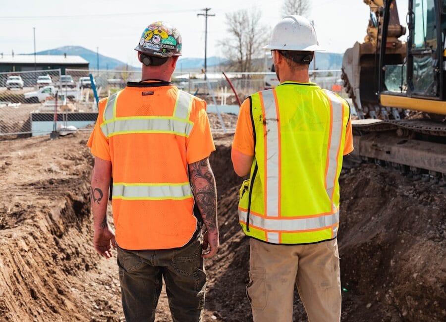 men in safety vests standing in front of a construction vehicle