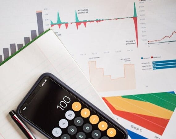 Top view of financial reports with a calculator app open on a smartphone.