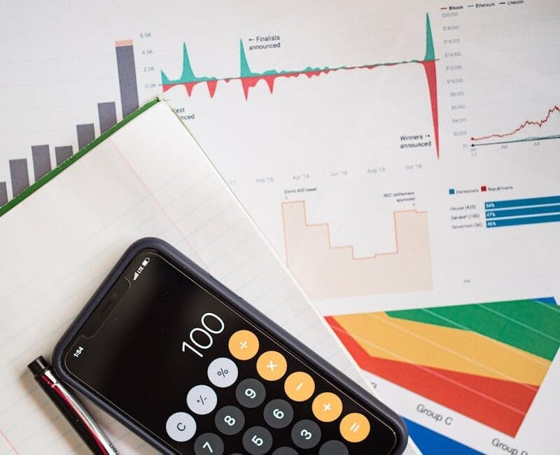Top view of financial reports with a calculator app open on a smartphone.